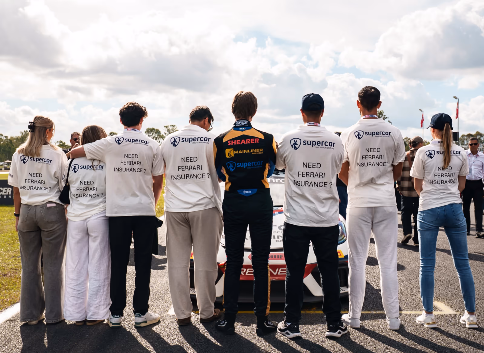 Supercar Insurance team members on the grid at Monochrome GT4 Australia wearing 'Need Ferrari insurance?' shirts
